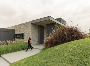 A contemporary residential exterior with stone walls and metal cladding.