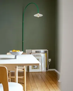 Modern dining room with wooden furniture, minimalist decor, and green pendant light.