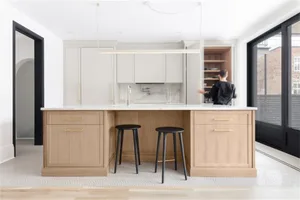 A modern residential kitchen featuring light wood cabinets and marble countertops.
