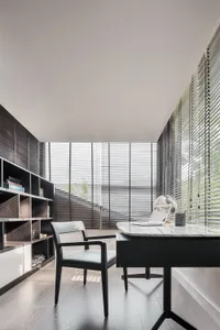Modern home office featuring a sleek black desk and comfortable chair, surrounded by large windows with natural light streami