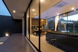 Modern minimalist living room featuring metal, glass, and concrete materials.