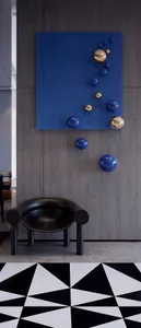 A sleek black curved chair with blue resin spheres hanging on the wall in a modern lobby setting.
