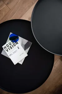 A sleek, modern black side table with a metallic finish, featuring a minimalist design and a blue circular object on top.