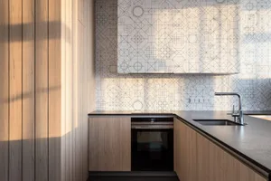 Modern kitchen with wooden cabinets and geometric tile backsplash.