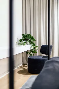 A modern living room featuring a fabric chair and blinds.