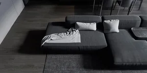 A modern living room featuring a grey fabric sectional couch with a blanket and pillows.
