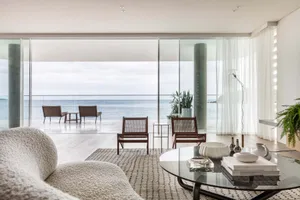 A modern living room featuring glass and wooden furniture with a sea/ocean view.