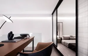 A modern minimalist bedroom featuring transparent glass walls and a sleek desk.