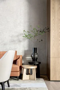 Minimalist living room featuring wooden furniture and a plant in a vase on a small wooden stool.