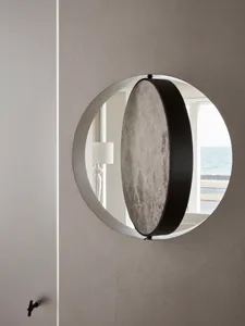 A modern decorative mirror with a metallic circular arc design mounted on a wall.