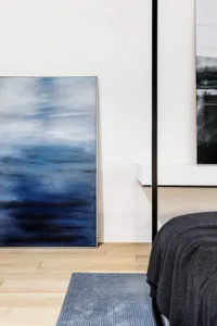 A minimalist interior design featuring a large abstract blue painting on a wall.