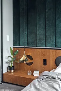 Modern bedroom featuring a wooden headboard and green fabric wall