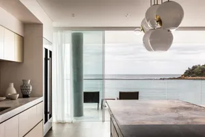 A modern kitchen with concrete countertops and a view of the ocean.