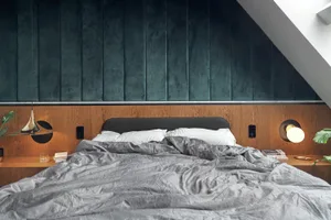 A cozy, modern bedroom with a textured velvet headboard, wooden walls, and cotton bedding.