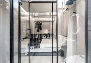 Modern hotel room with glass walls and minimalist decor.