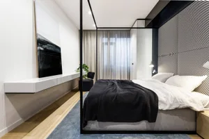 Modern minimalist bedroom featuring a high-tech design with fabric bedding, wooden flooring, and glass elements.