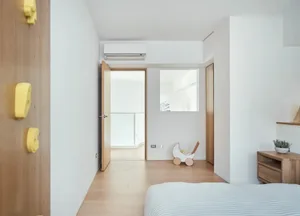 Minimalist bedroom with wooden furniture and a white air conditioner unit mounted on the wall.
