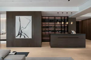 A modern minimalist residential bar with dark wood finishes, illuminated shelves, and a sleek countertop.