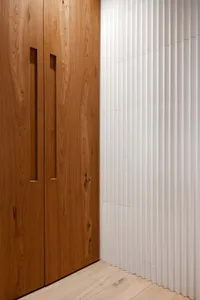 Modern wooden cabinets with vertical grain texture and light hardwood flooring.