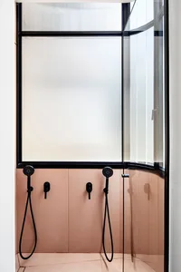 A minimalist bathroom with a glass door and pink floor tiles.