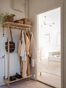 A minimalist wooden clothing rack with clothes and accessories.
