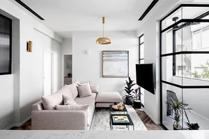 Modern living room with minimalist decor, neutral tones, and sleek white pendant light fixture.