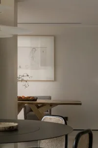 A modern dining room featuring a live-edge wooden table with a black circular dining table and woven chairs.