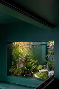 A modern living room with a greenhouse filled with various plants.