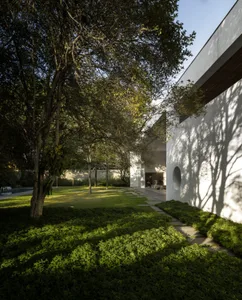A modern residential space featuring concrete structures and lush greenery, with a path leading to a building entrance.