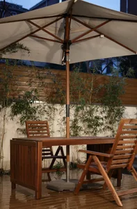 Modern outdoor furniture set with wooden table, chairs, and parasol.