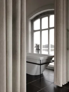Modern minimalist bathroom featuring a ceramic bathtub with metal fixtures.