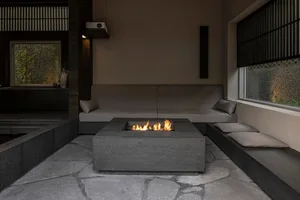 A minimalist residential space with concrete flooring, a fire pit, and a comfortable seating area.