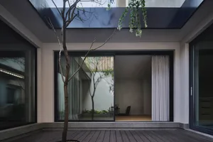 A minimalist residential interior with glass walls and wooden flooring.