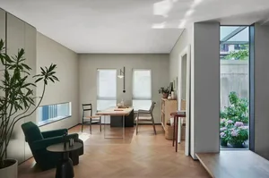 A minimalist residential space featuring wooden flooring, glass windows, and metal accents.