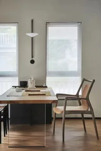 A modern home office with wooden furniture, a minimalist desk, and a hanging light fixture.