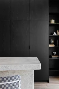 A modern kitchen with black cabinetry and a concrete countertop.