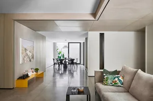 A modern living room with concrete walls and a glass partition.