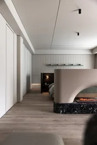 Modern minimalist bedroom with wooden floors, marble divider, and glass wall, featuring a comfortable bed with elegant beddin