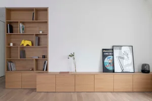 A modern minimalist interior featuring a wooden shelf with books and decorations.