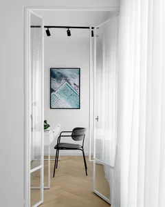 A modern minimalist office space featuring a glass door, metal chair, and wooden floor.