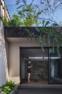 A modern outdoor gym with concrete flooring and walls, featuring a stone wall and greenery.