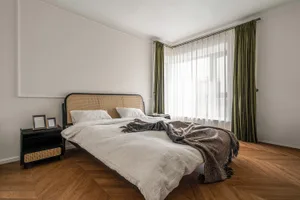 Modern minimalist bedroom featuring a woven headboard and wooden floor.