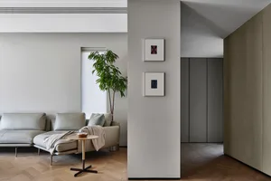 A minimalist living room with a gray leather sofa and matching armchair, featuring a small round side table with a bowl, fram
