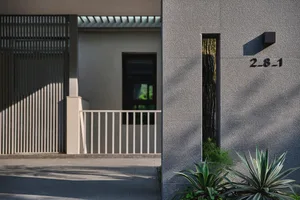 Modern building entrance with a concrete facade and a narrow vertical glass window.