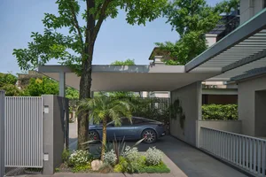 A modern exterior carport with greenery and plants, featuring a sleek car parked underneath.
