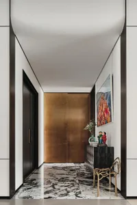 A modern entrance hall featuring metal, leather, and marble materials.