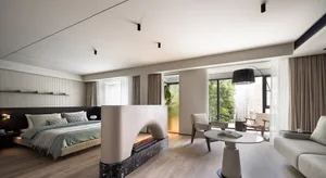 Modern minimalist bedroom with white bed, fireplace, and wooden floor.