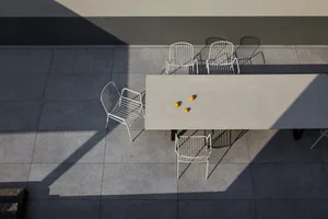A minimalist outdoor seating area featuring a concrete table and metal chairs.