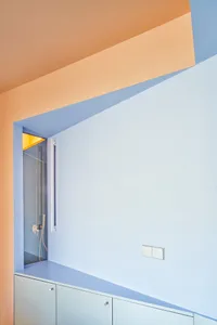 Modern bathroom with glass shower enclosure, minimalist design, light blue walls, and orange ceiling trim.