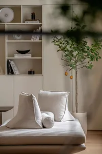 A modern living room with light-colored furniture and a potted plant.